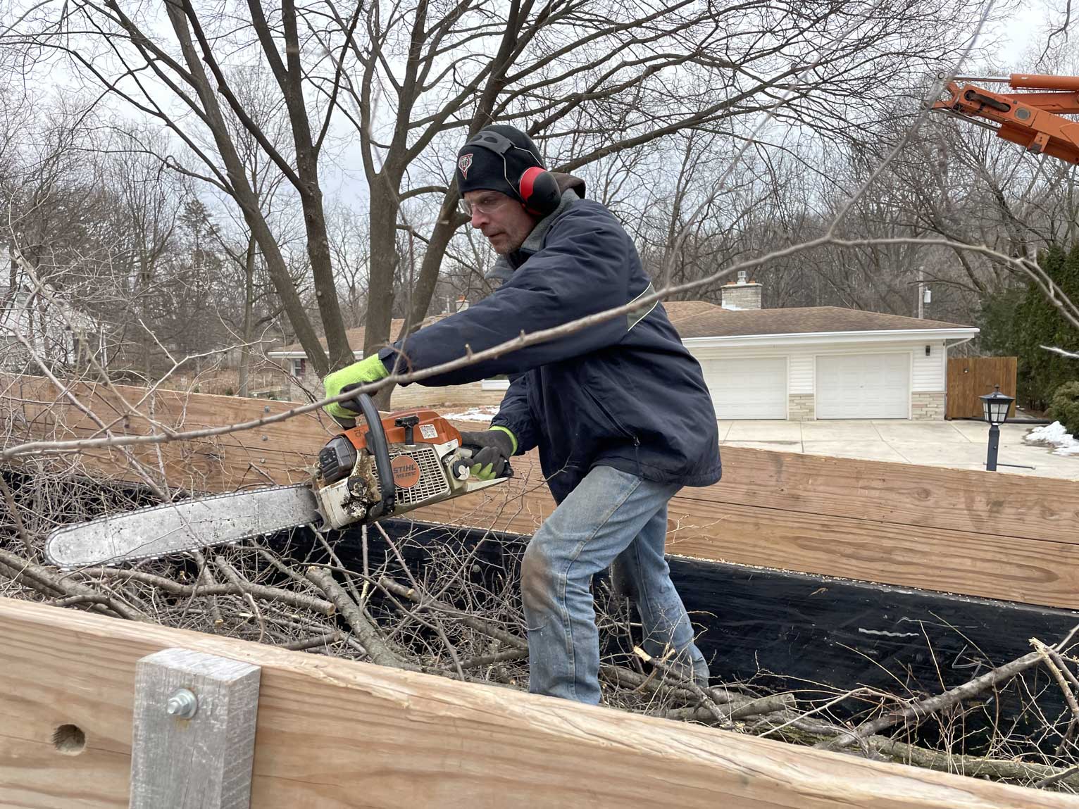 man cutting tree branches with chainsaw